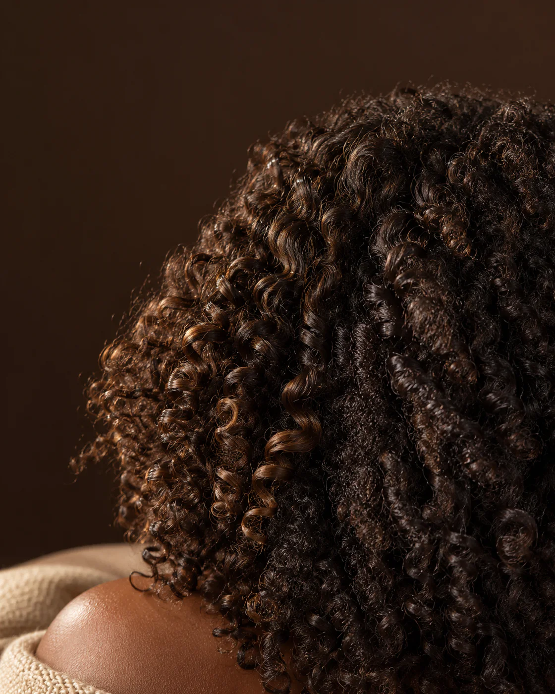 Boucles et cheveux crépus naturels éclairés latéralement, avec des reflets réalistes par touches